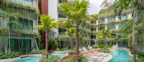 A hotel courtyard with a swimming pool, palm trees, and lounge chairs.