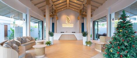 A modern reception area with a wooden ceiling, a reception desk, and a Christmas tree.