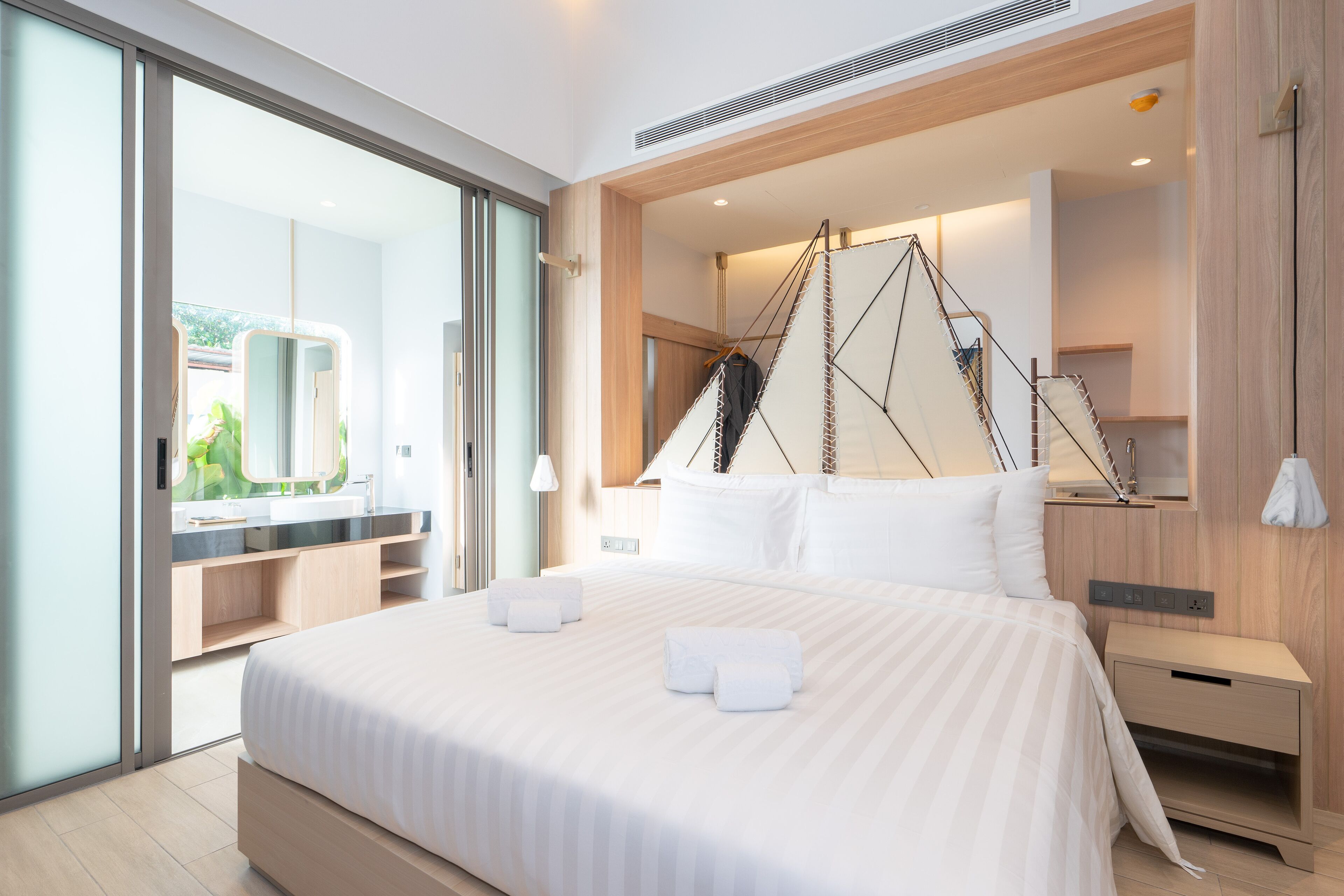 A modern hotel room with a large bed, a walk-in closet, a large mirror, and a view of the outdoors.
