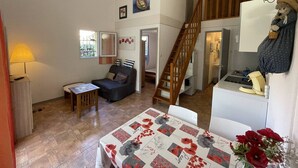 A cozy living room with a sofa, a small table, a staircase, and a kitchen area. - Charming 2BR Villa with Pool, Tennis & BBQ - 200m from Beach, Saint-Cyprien (Saint-Cyprien)