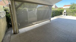 A covered outdoor area with a metal gate, a tiled floor, and a small outdoor grill. - Charming 2BR Villa with Pool, Tennis & BBQ - 200m from Beach, Saint-Cyprien (Saint-Cyprien)
