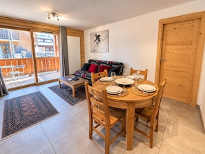 A dining area with a round wooden table set for four, surrounded by wooden chairs.