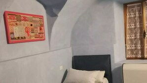 A small, single-bed room with a simple bed, a pillow, and a wall-mounted picture. - Guesthouse La nuvola (Sagliano Micca)