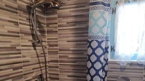 A bathroom with a shower, a sink, and a window with patterned curtains. - Guesthouse La nuvola (Sagliano Micca)