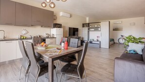 A modern kitchen with a dining area, featuring a wooden table, black chairs, and a hanging light fixture. - Living Siena - Apartment "Strade Bianche" (Siena)