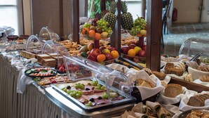 A buffet with various food items including fruits, sandwiches, and pastries.