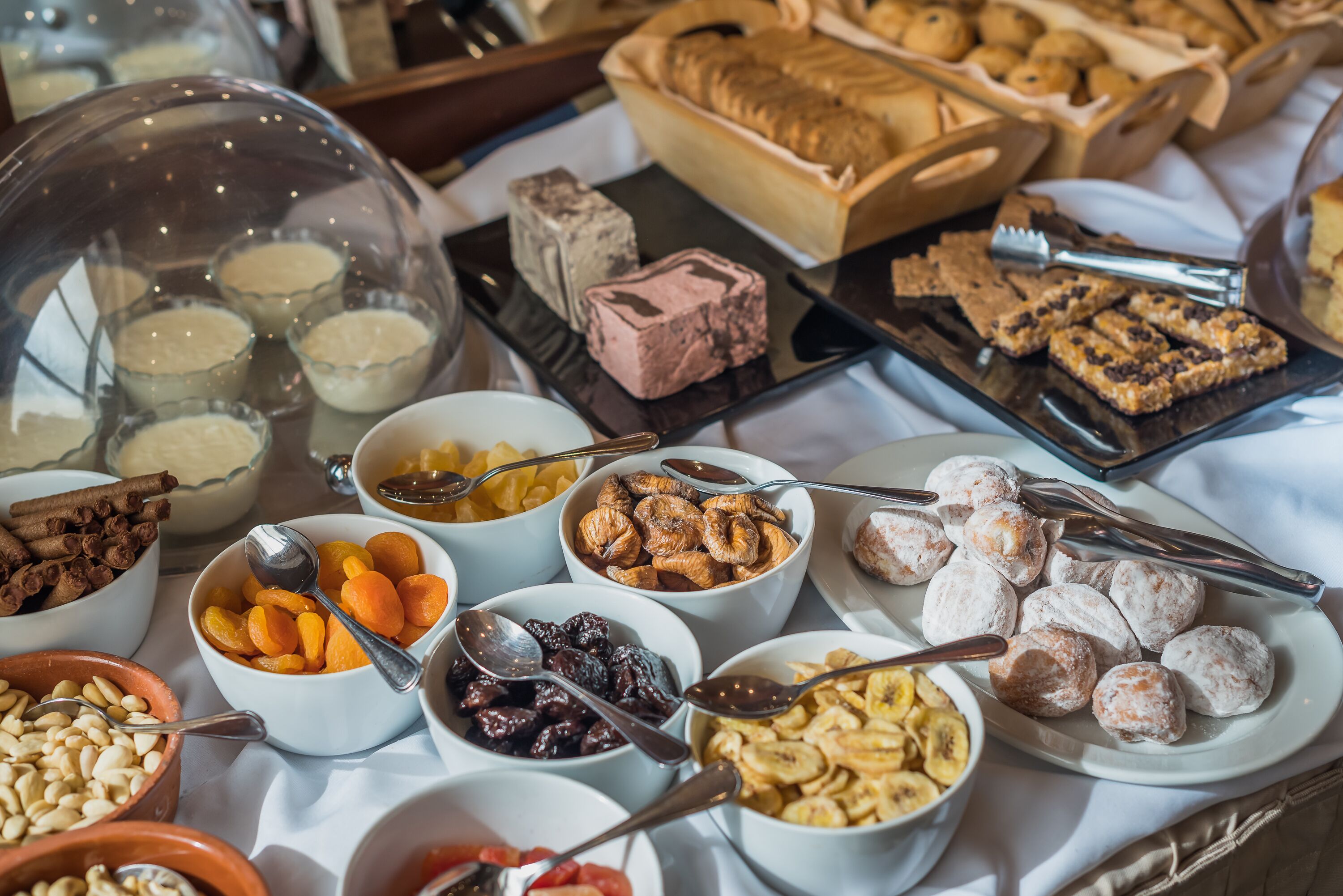 Un bufé con diversos alimentos, incluyendo bollería, frutas y frutos secos.