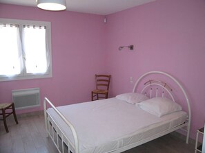 Un dormitorio con una cama individual, una silla, un radiador y una ventana con cortinas.
