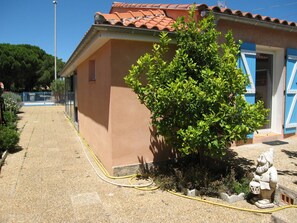 Un edificio con techo de tejas, un jardín con un árbol pequeño y una estatua.