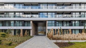 Ein modernes Gebäude mit einem gepflasterten Weg, der zu einem Eingang mit der Aufschrift "117K" führt.