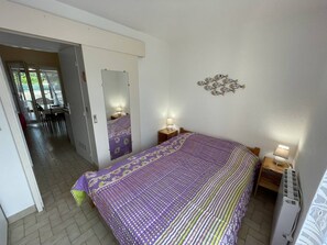 A bedroom with a bed, bedside tables, a mirror, and a decorative wall piece.