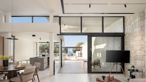 Una sala de estar moderna con comedor, televisor de pantalla plana y pared de piedra.