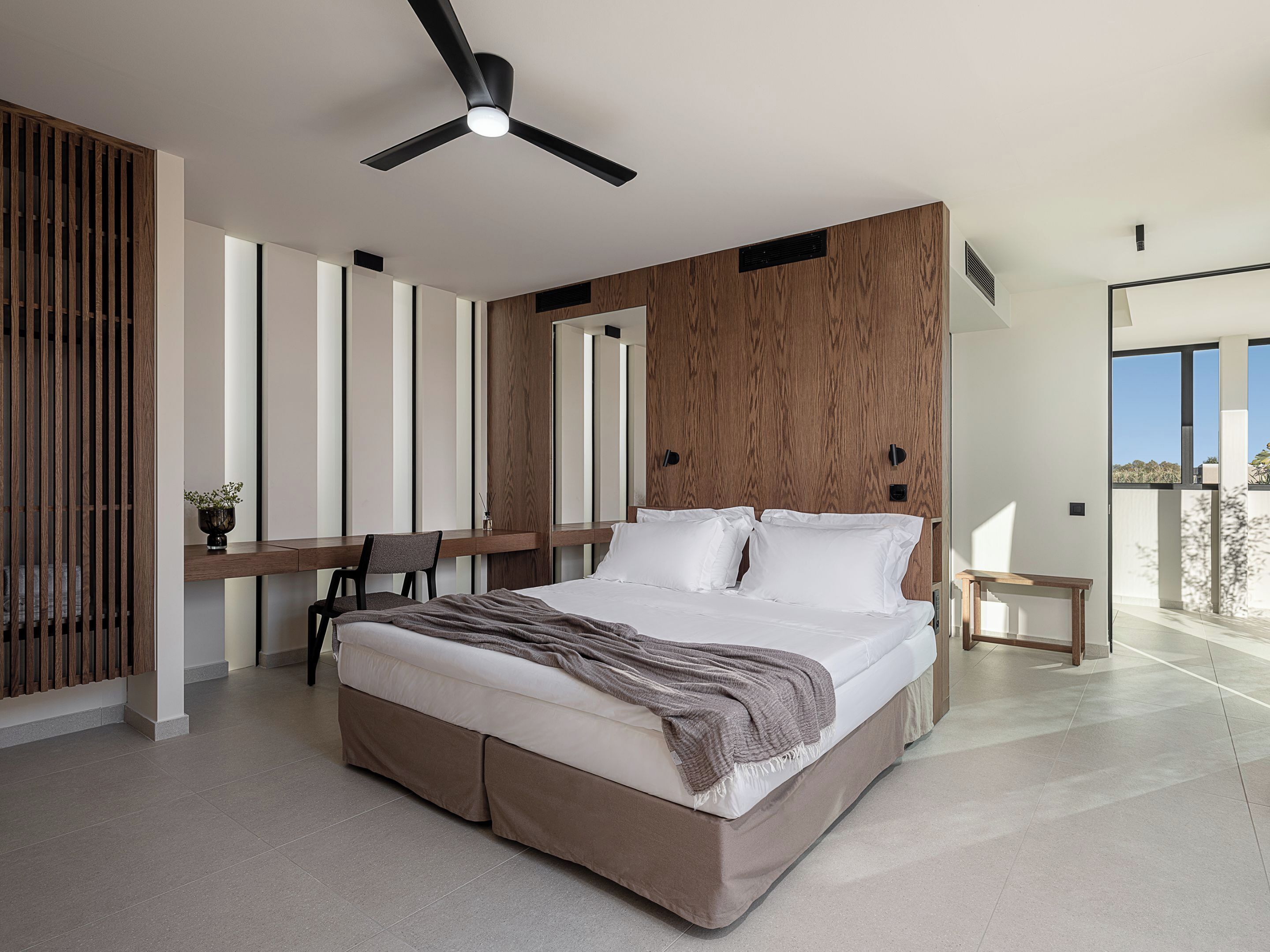 Un dormitorio moderno con una cama grande, un escritorio y un ventilador de techo.