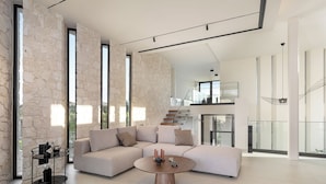 Amplia sala de estar con un sofá modular grande, una mesa de centro redonda y una vinoteca.