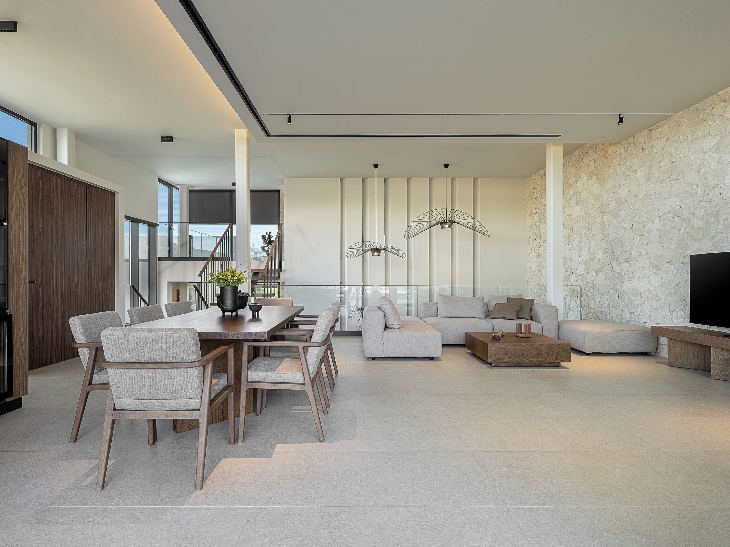 A modern living room with a dining area, a sofa set, and a TV.