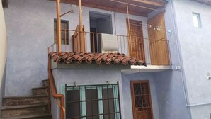 A two-story building with a balcony, a staircase, and a gate. - Apartment in the center of Sagliano Micca (Sagliano Micca)