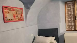 A small, single-bed room with a simple bed, a pillow, and a wall-mounted picture. - Apartment in the center of Sagliano Micca (Sagliano Micca)