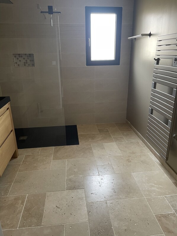 A bathroom with a shower, a window, and a towel rack.