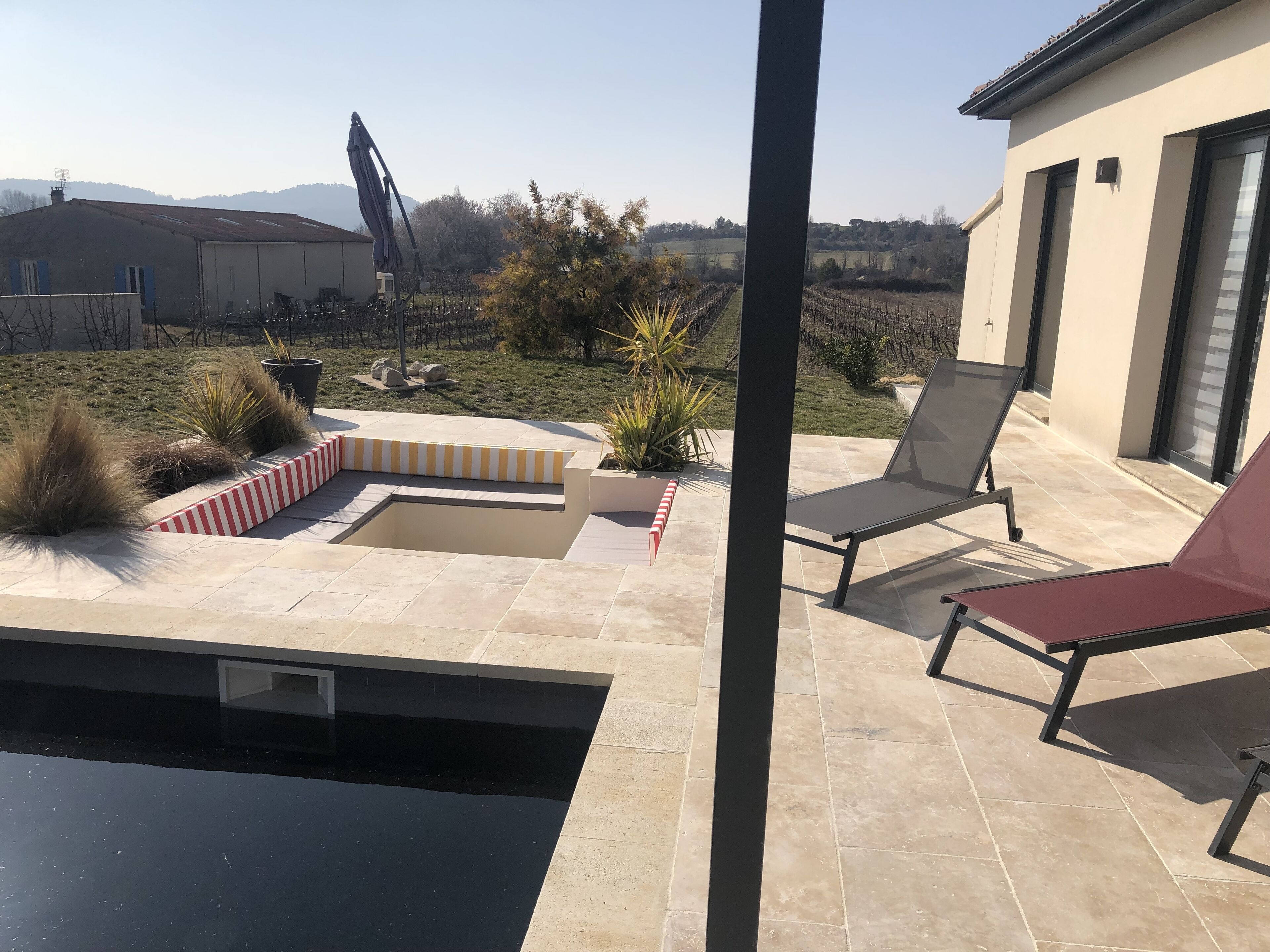 A patio with a pool, outdoor seating, and a view of the countryside.