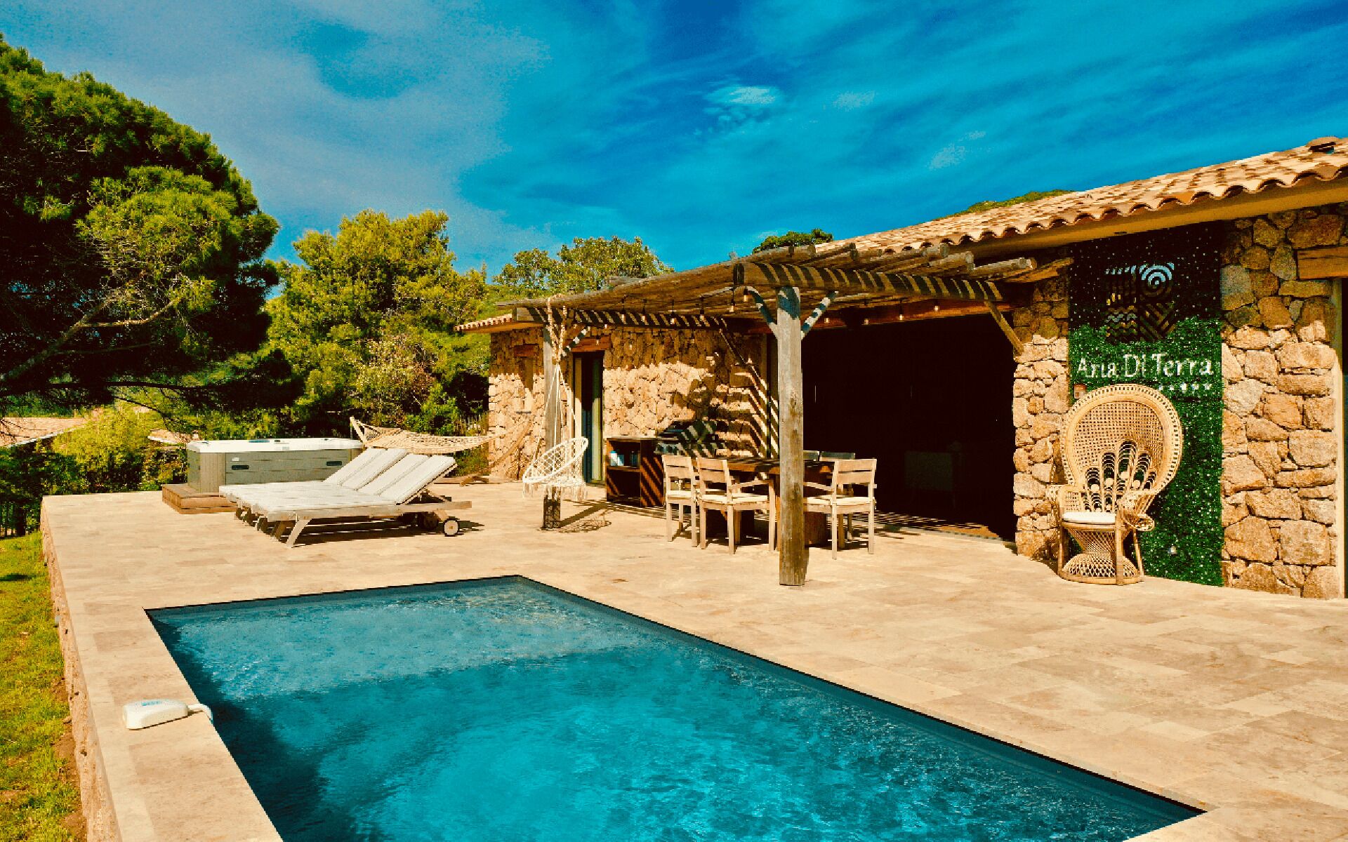 Un espace piscine avec des chaises longues et un bâtiment en pierre sur lequel est apposée une enseigne indiquant « Albergo Di Terra ».