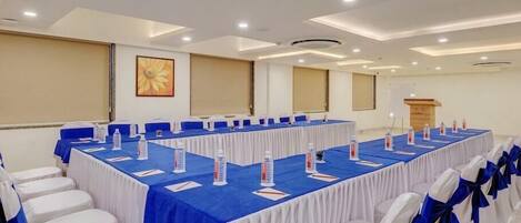 A conference room with a long table, white chairs with blue sashes, and a podium.