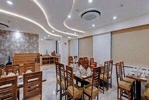 Uma área de refeições com mesas e cadeiras de madeira, piso de mármore e design moderno no teto.