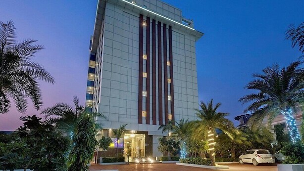 A modern hotel with a prominent vertical design, a well-lit entrance, and a landscaped outdoor area with palm trees. - Click Collection Jaipur (Jaipur)