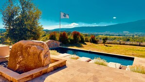 A pool area with stone steps, a flag, and a view of distant mountains. - Our Estate located in Figari in Southern Corsica, is made up of several authenti (FIGARI)