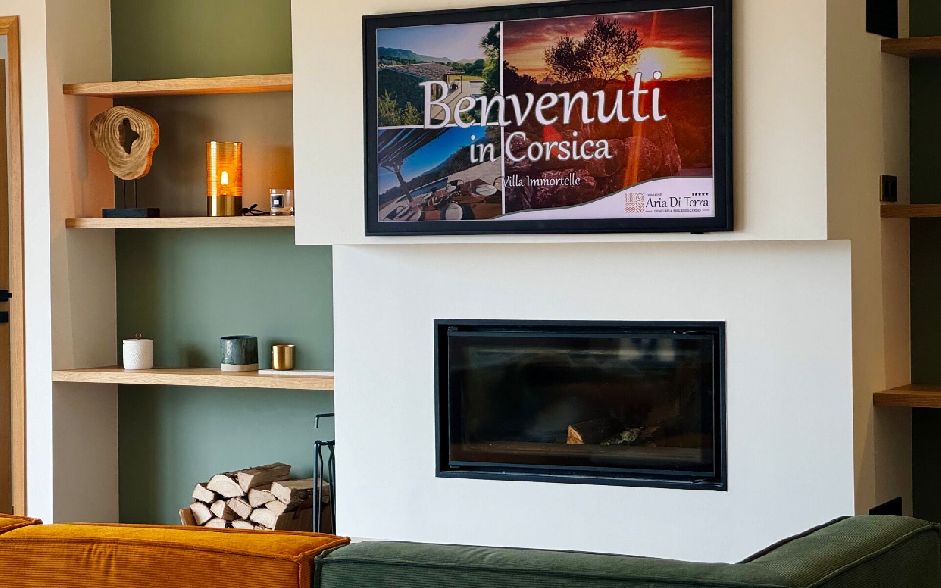 A framed welcome sign for 'Benvenuti in Corsica' above a fireplace.
