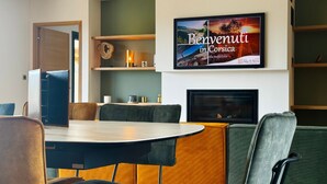 A modern hotel room with a round dining table, comfortable seating, a fireplace, and a framed welcome sign. - Our Estate located in Figari in Southern Corsica, is made up of several authenti (FIGARI)