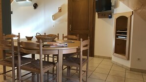 Un comedor con una mesa y sillas de madera, una cesta y un televisor montado en la pared.