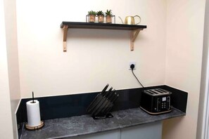 Compact kitchen area with a toaster, paper towels, and a knife block on the countertop.