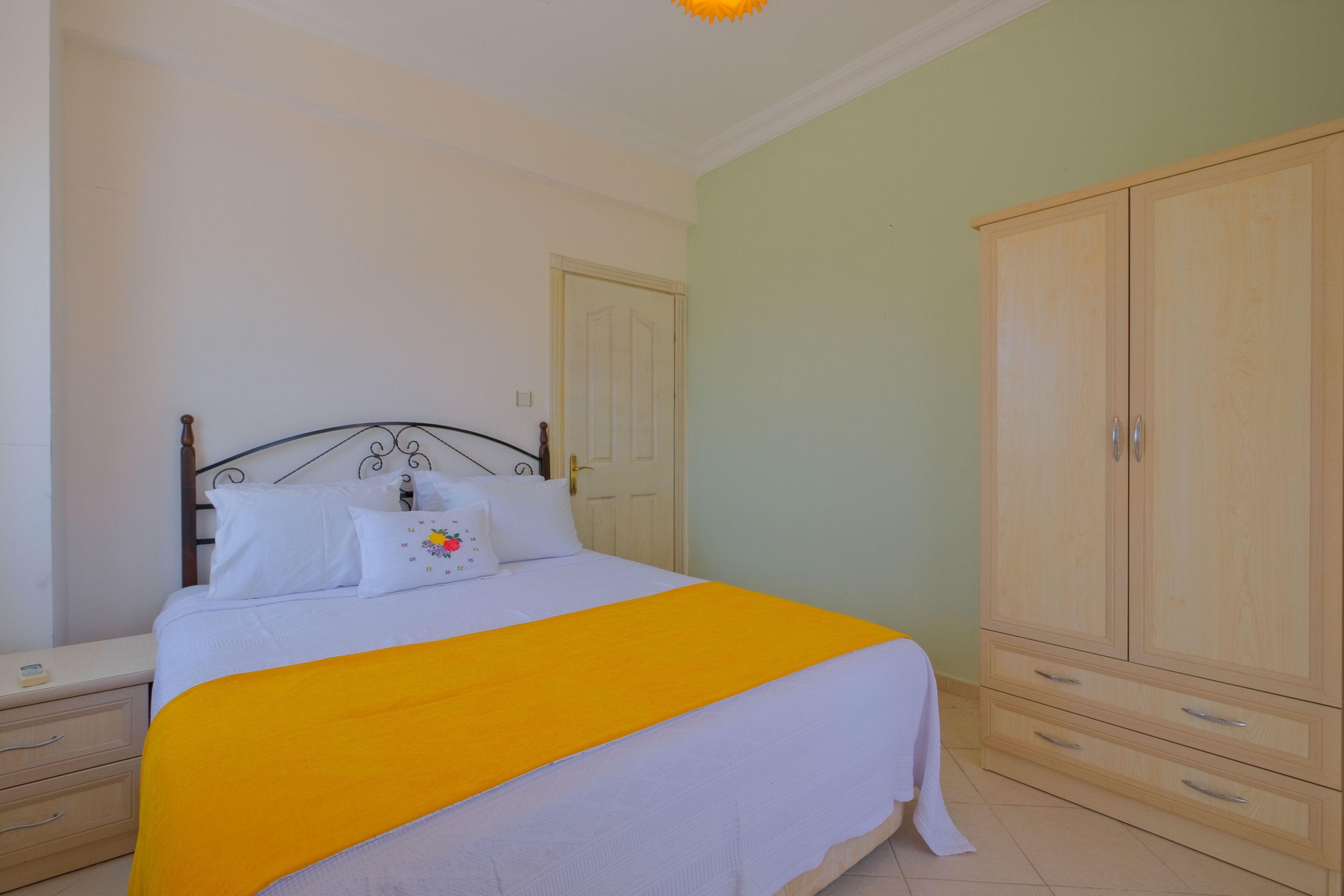 Ein Schlafzimmer mit Bett, Nachttisch, Kleiderschrank und Tür.