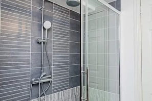 Bathroom features a shower with a glass door and wall-mounted showerhead.