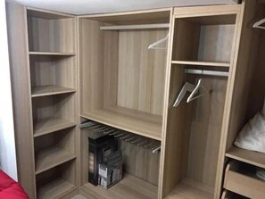 Ample storage space is available in this room with a wardrobe featuring multiple compartments and shelves.