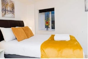 Enjoy a restful night's sleep in this inviting room, featuring a comfortable bed and a beautiful painting above.