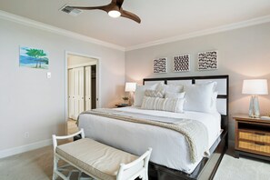 A bedroom with a bed, bedside tables, a bench, and a ceiling fan.