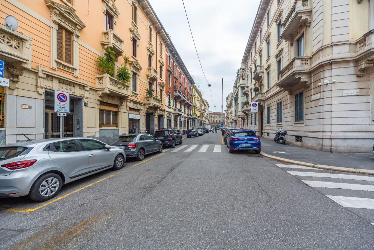 A street lined with historic buildings, parked cars, and a pedestrian crossing.