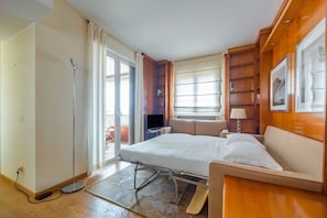 Une chambre d’hôtel équipée d’un lit, d’un bureau, d’une télévision, d’une fenêtre avec des stores et d’une lampe de chevet.