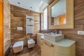Une salle de bain moderne avec un grand miroir, un lavabo, un bidet et des toilettes.
