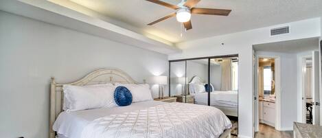A bedroom with a bed, a ceiling fan, a nightstand, and a dresser.