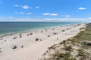 A beach with a volleyball court, umbrellas, and beachgoers. - Flash Sale Summer House 805A 3/2 sleeps 10 (Orange Beach)