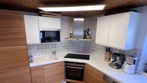 Eine moderne Küche mit Holzschränken, einem Backofen, einer Spüle und einer Kaffeemaschine.