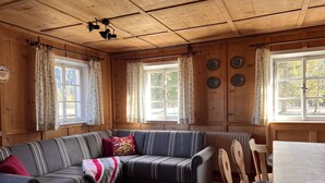 Ein gemütliches Blockhaus-Interieur mit einer Couch, einem Esstisch und Holzwänden.