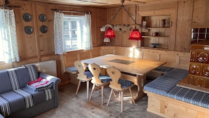 Ein gemütliches Blockhaus-Interieur mit einem Holzesstisch, Bänken, einer Couch und einer Heizung.
