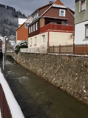 Un étroit canal où l’eau s’écoule, bordé d’un côté par un mur de pierre et de l’autre par une clôture en bois.