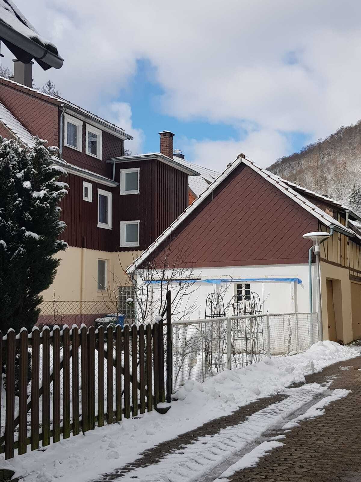 A residential area with houses, a wooden fence, and a snow-covered path.