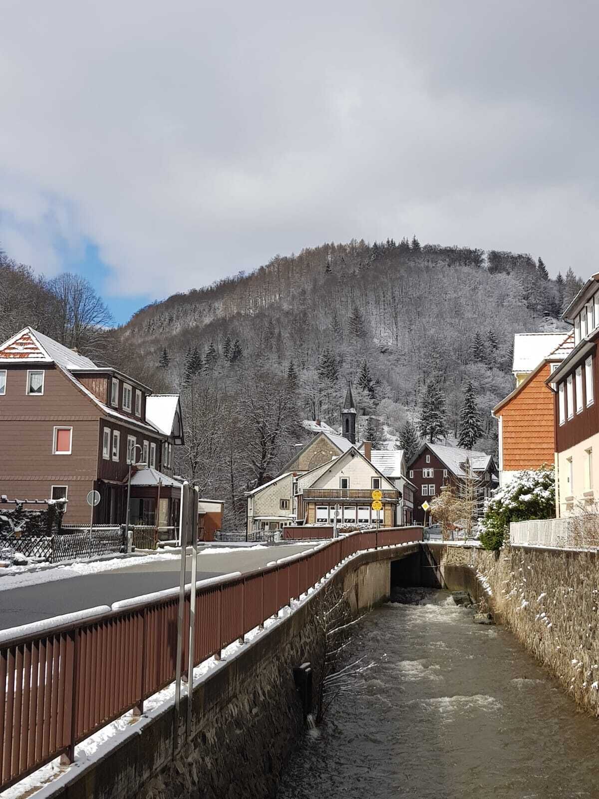 Un puente sobre un río con edificios a ambos lados, una montaña al fondo y un paisaje nevado.
