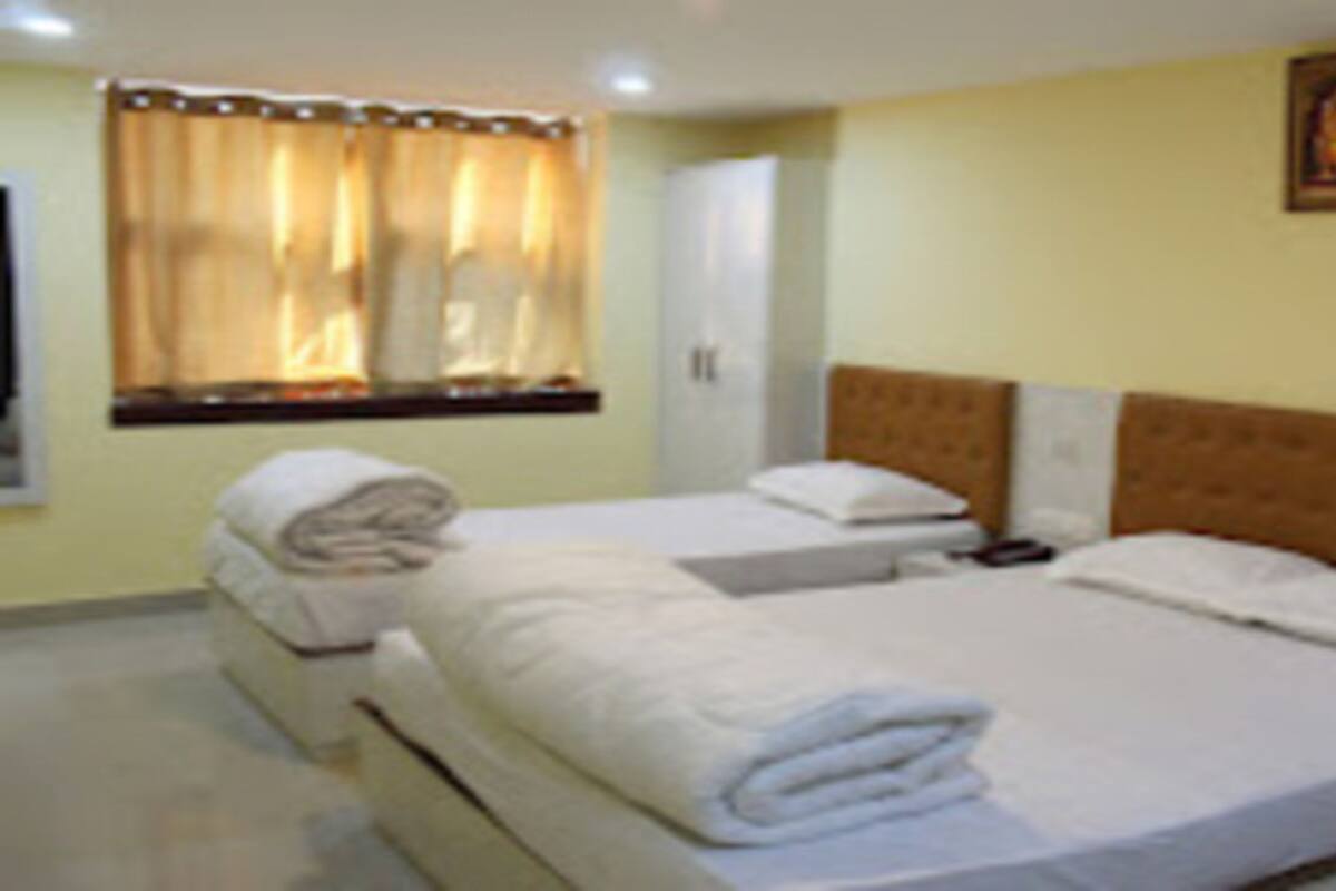 A hotel room with a bed, bedside tables, a wardrobe, and a window with curtains.