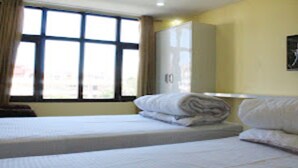 A hotel room with two beds, a window with curtains, a wardrobe, and a painting on the wall. - MeroStay 021 Hotel Ganga Sagar (Kathmandu)